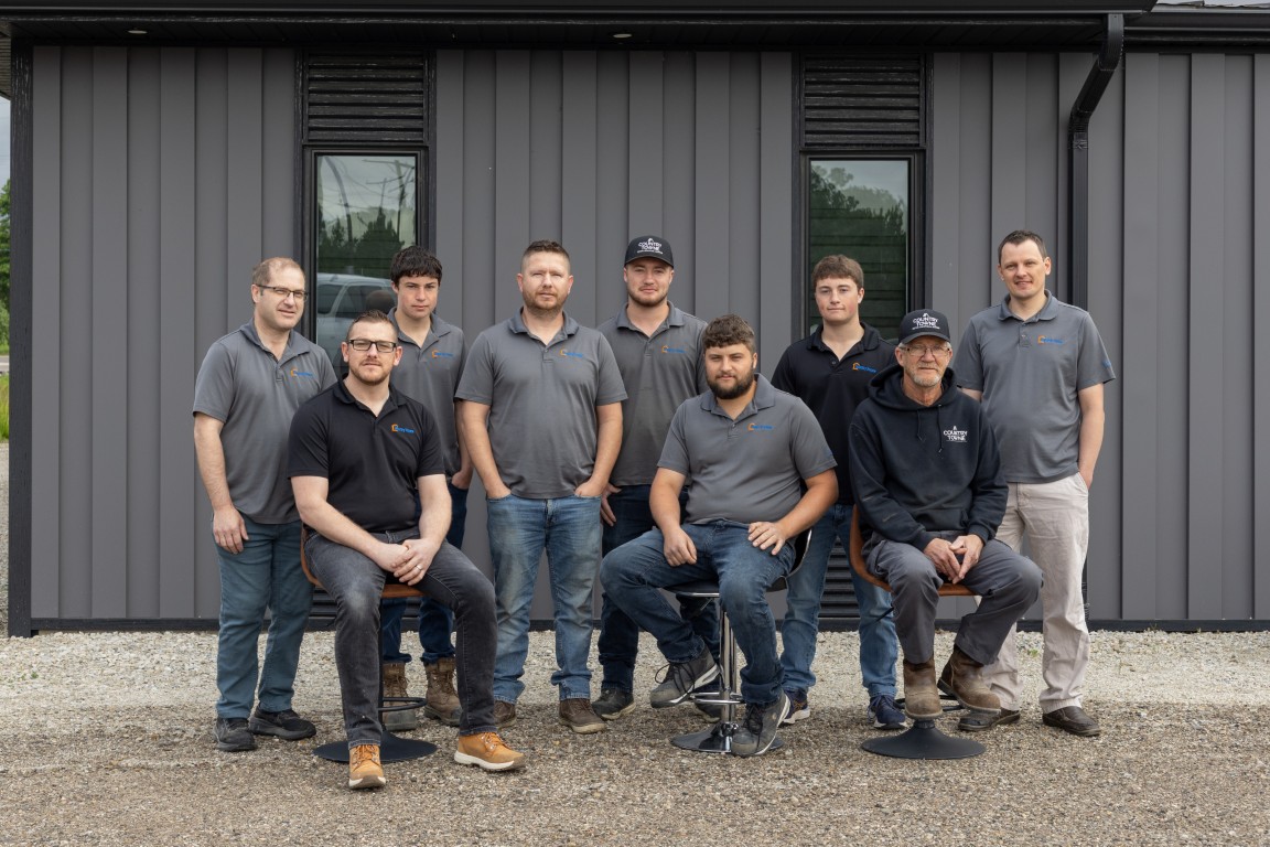 Country Towne team standing in front of dark vertical metal siding, proudly serving Ontario customers