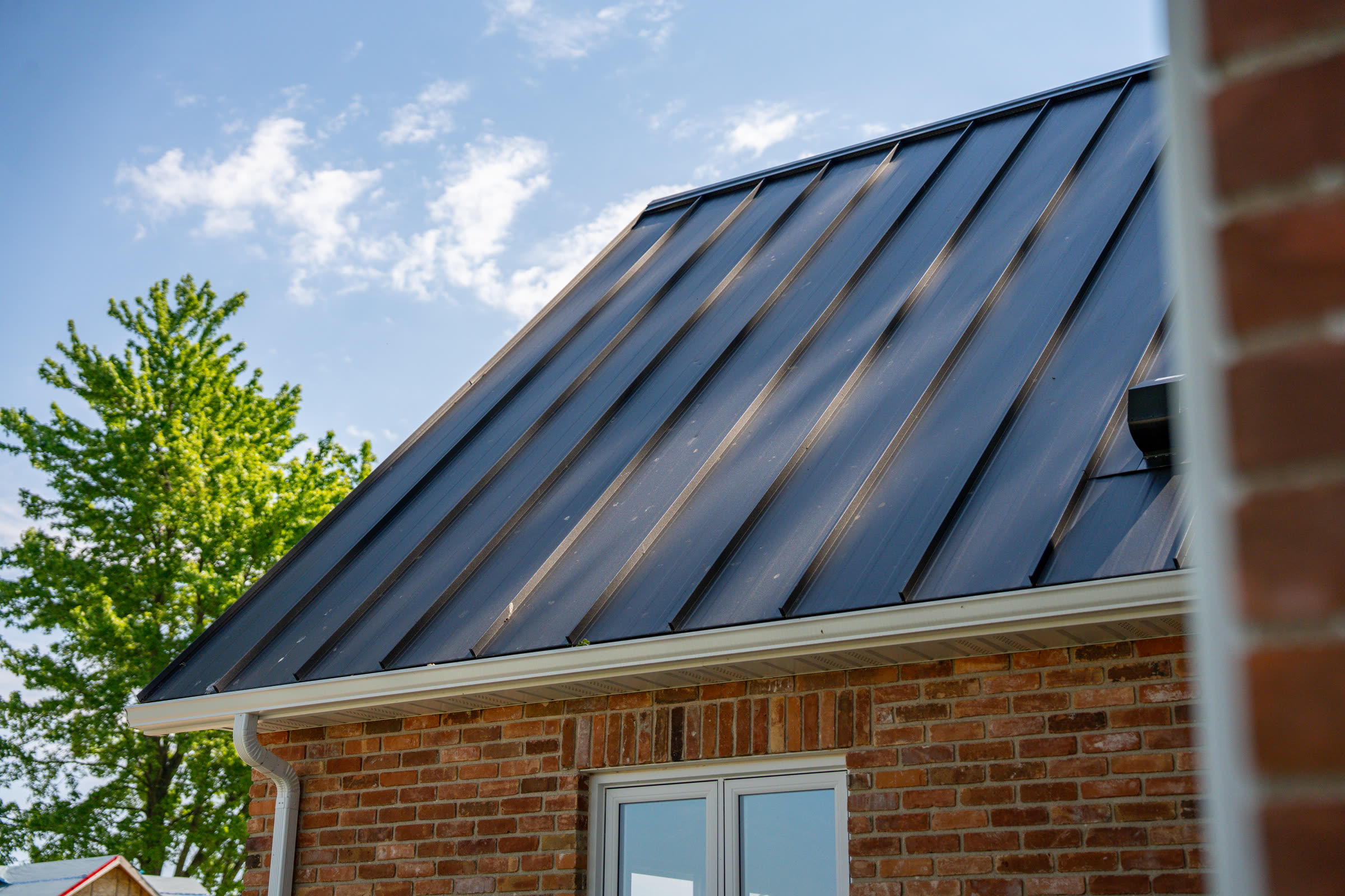 Close detail of dark SS550 SnapLock metal roof panels meeting the white eaves on the Dresden home