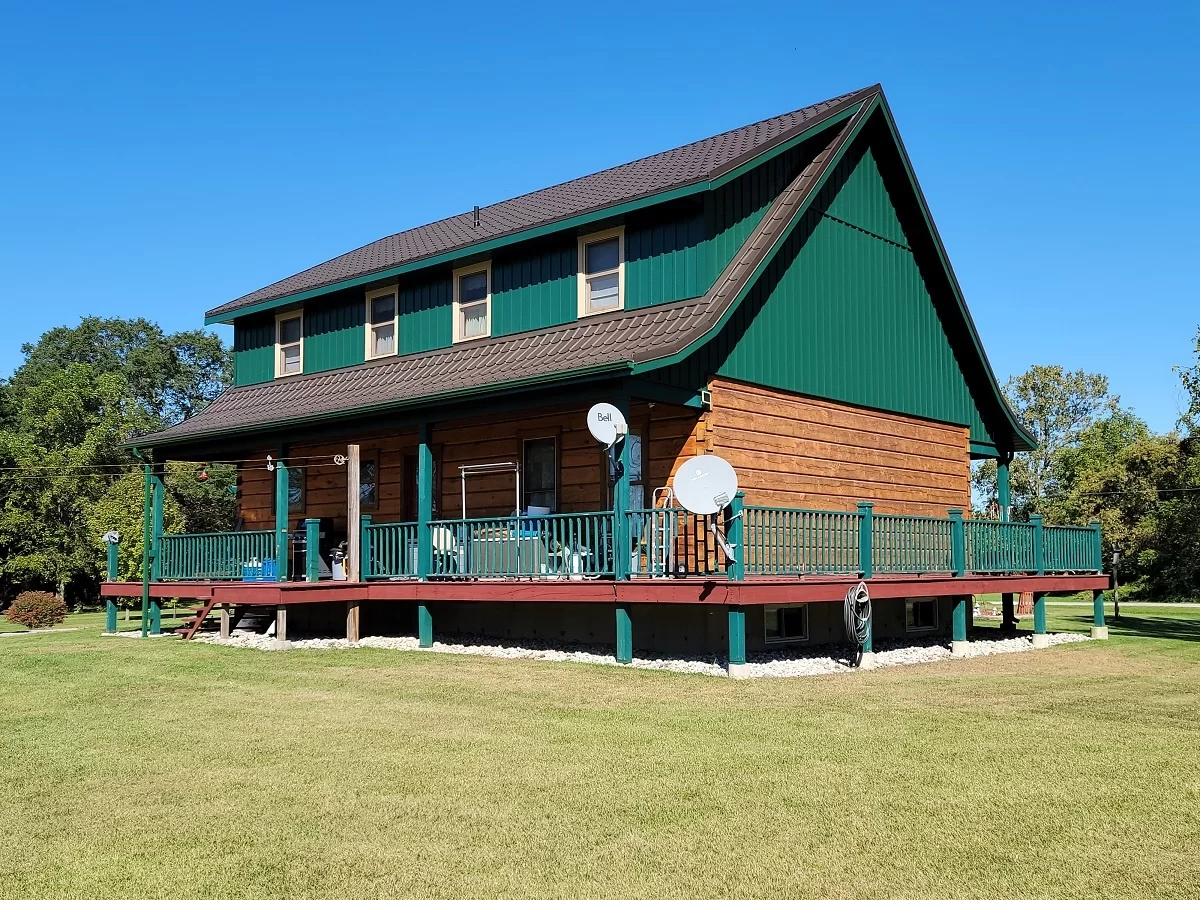 Country-style home featuring green vertical metal siding and woodgrain cladding — CountryTowne installation highlighting mixed materials and rural charm.