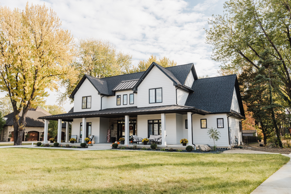 Modern farmhouse with white horizontal lap siding and black standing seam metal roofing — premium residential project by CountryTowne.