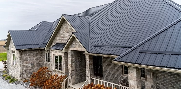 Custom stone home with black Tuff Rib metal roofing — exposed fastener panels by CountryTowne offering long-lasting protection and bold architectural style.
