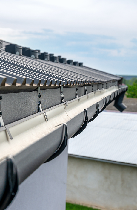 Close-up of black half-round eavestrough installed with CountryTowne metal roofing — combining heritage style with effective water drainage.