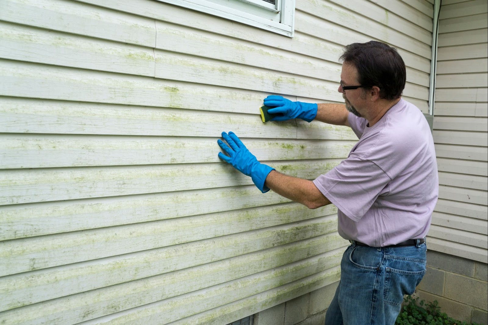 a man cleaning his house' metal siding.